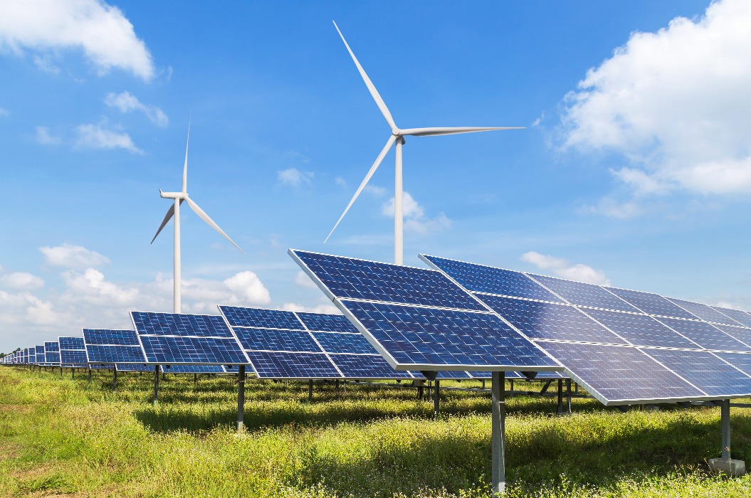 Feld mit Solarpanels und Windrad im Hintergrund